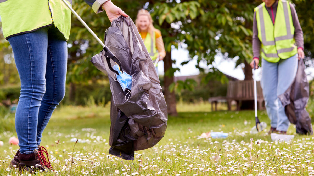 Three people in a field picking up litter.