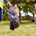 Three people in a field picking up litter.