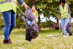 Close Up Of Female Volunteers Picking Up Litter In The Countryside Three people in a field picking up litter.