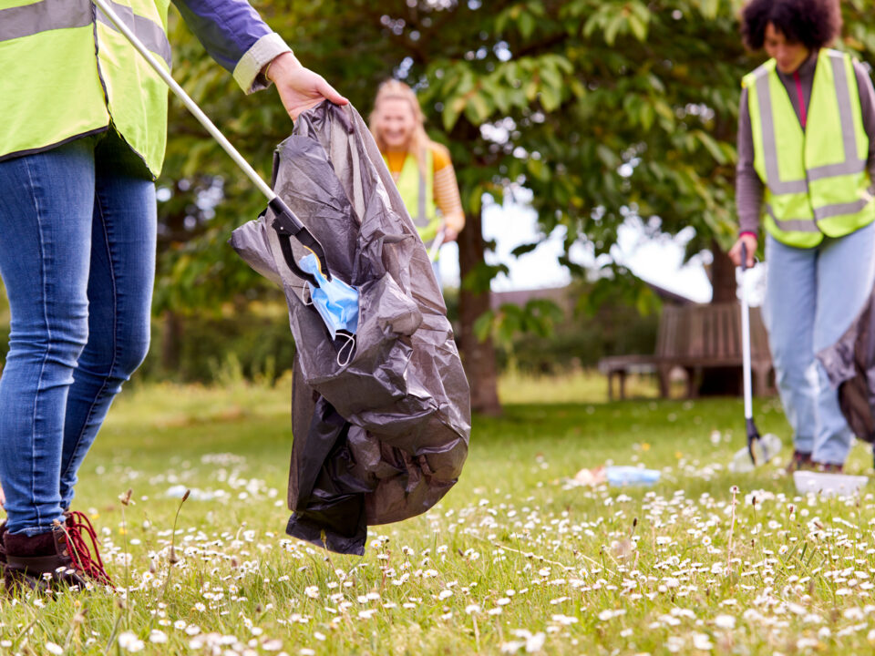 Three people in a field picking up litter.